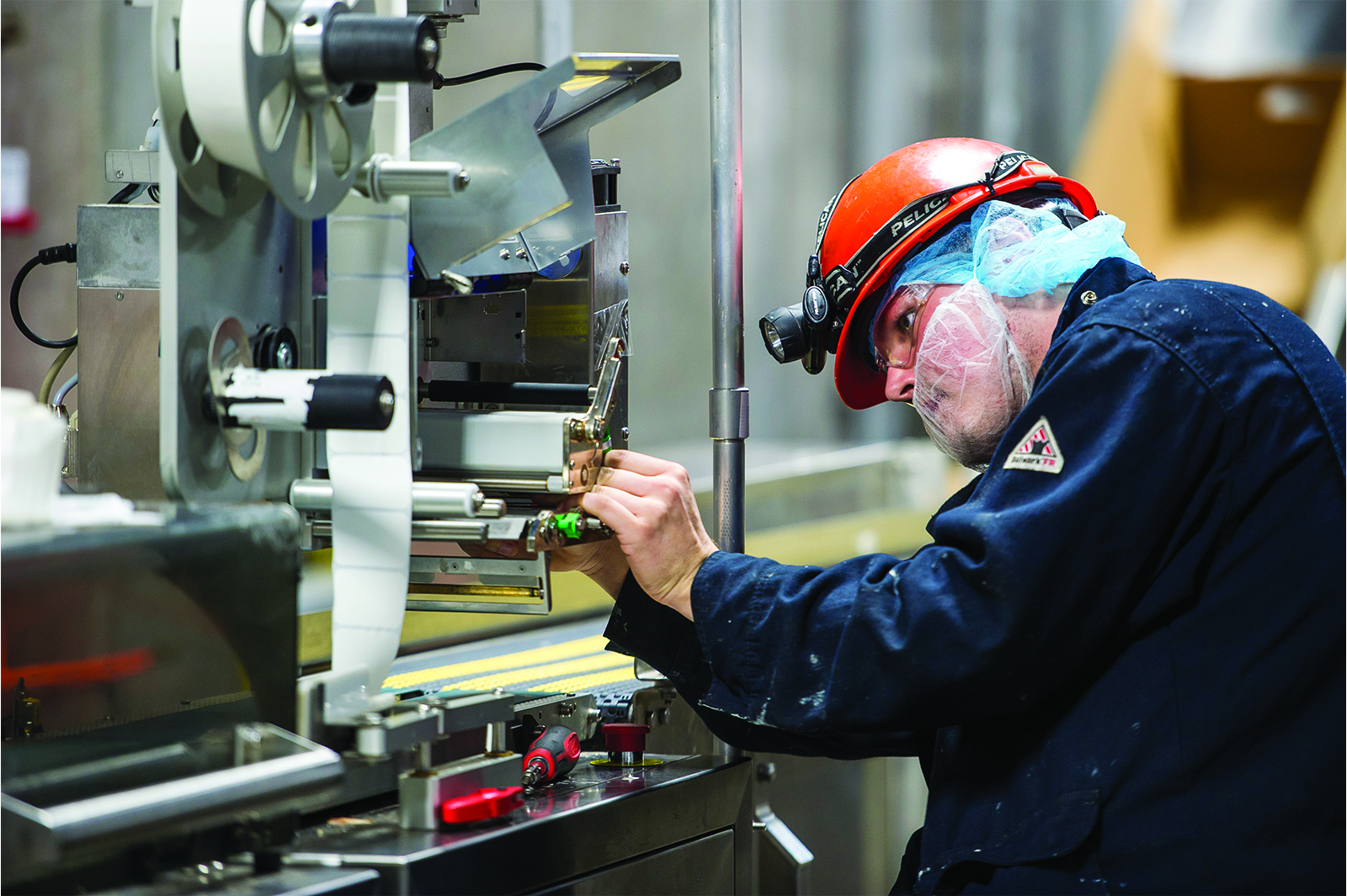 An employee fixing a machine on an assembly line.