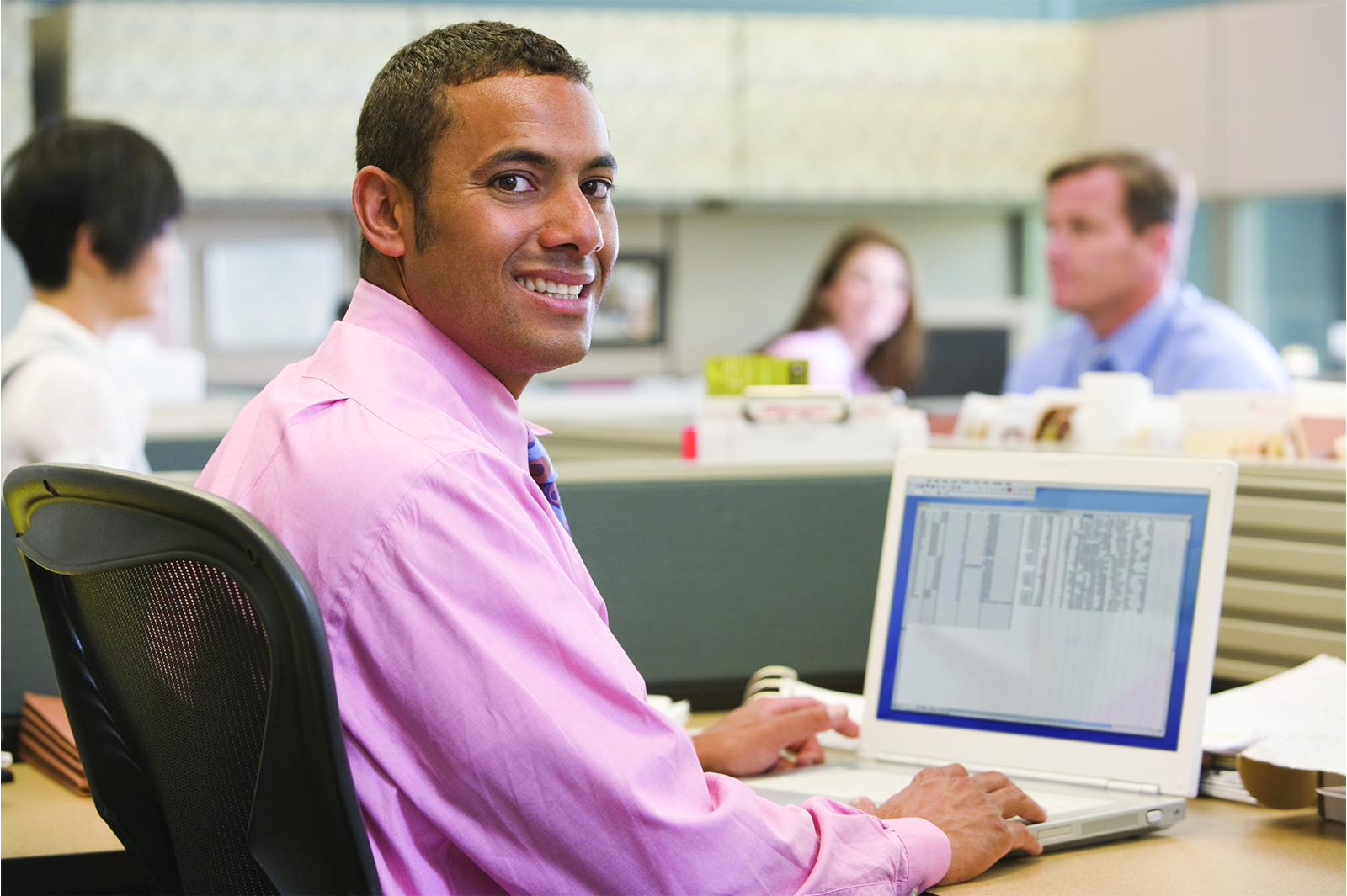 An employee sitting at computer making eye contact.