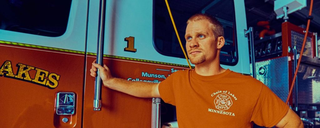 Firefighter leaning on fire truck.