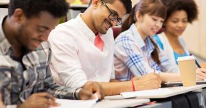 Adult students sitting at desks taking notes while smiling